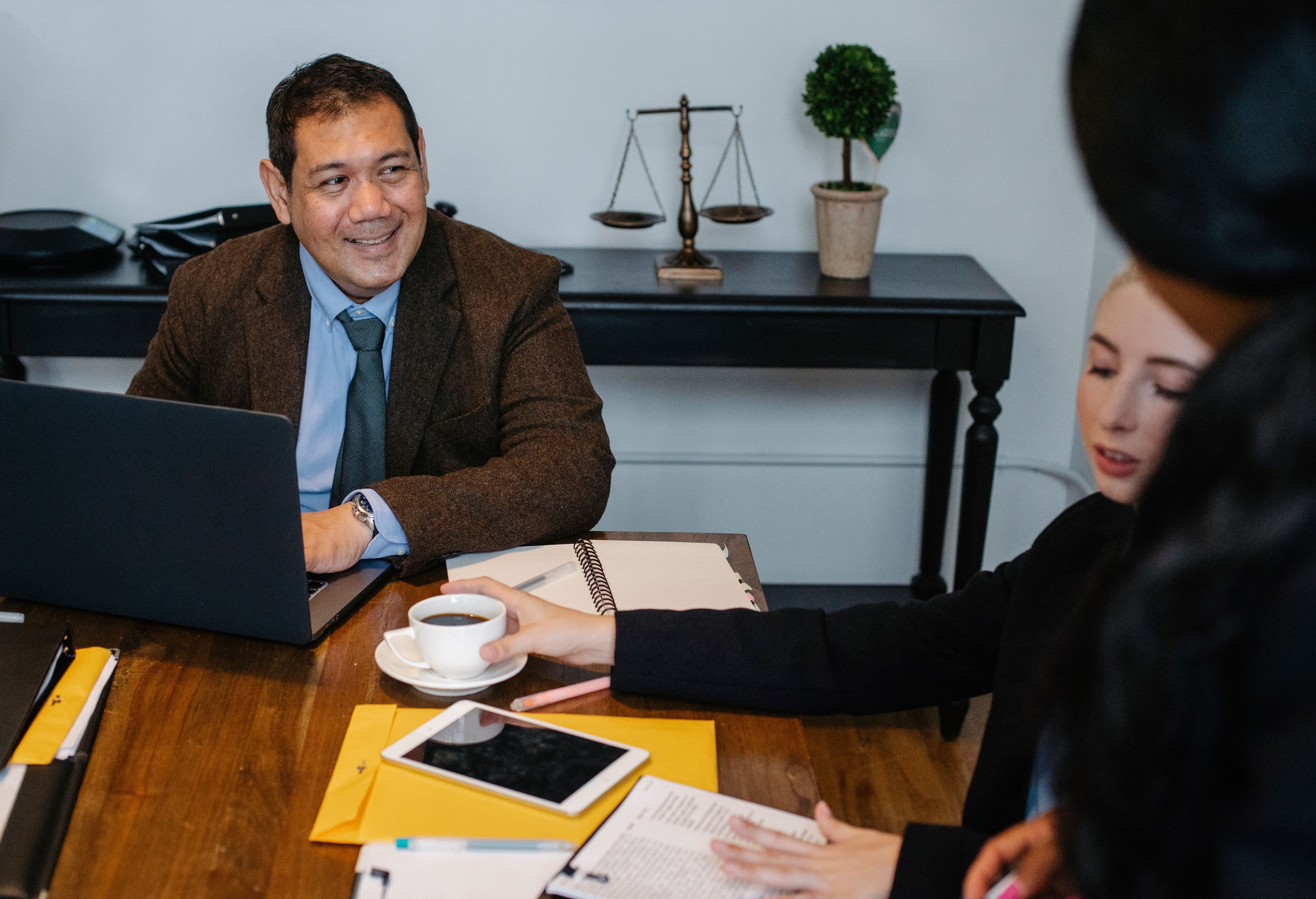 Professionals discussing an evaluation with documents, a laptop, and a tablet