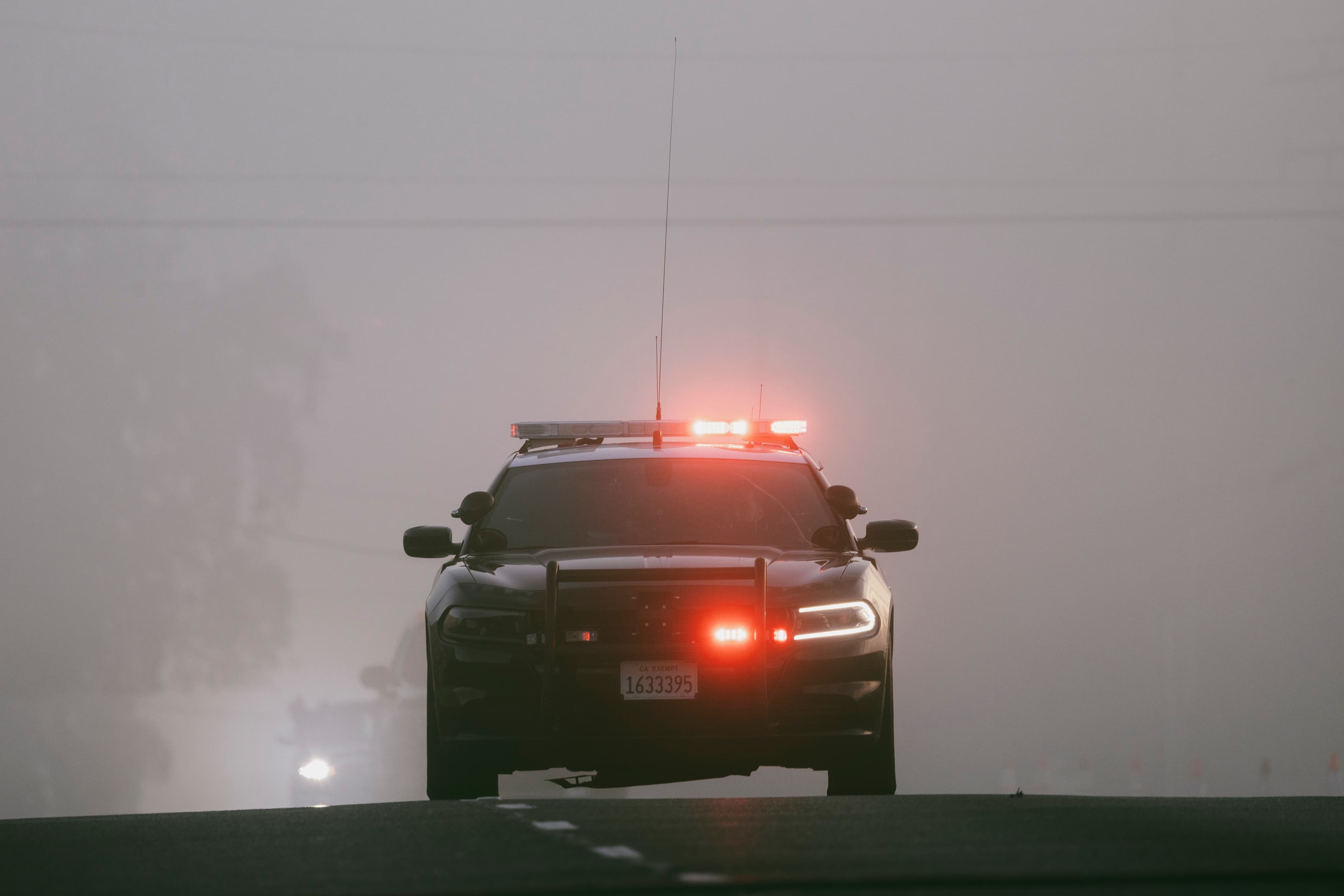 Public safety vehicle approaching through fog with emergency lights activated