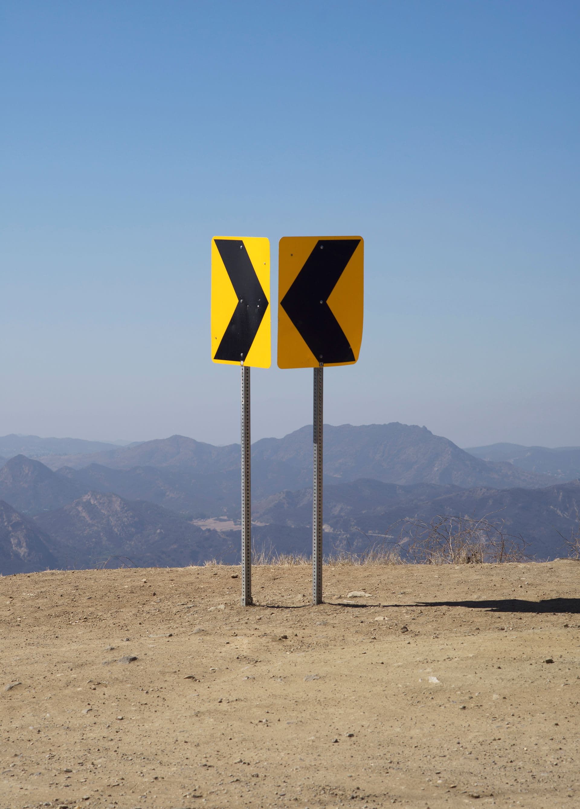 Rural directional road signs overlooking a mountainous landscape