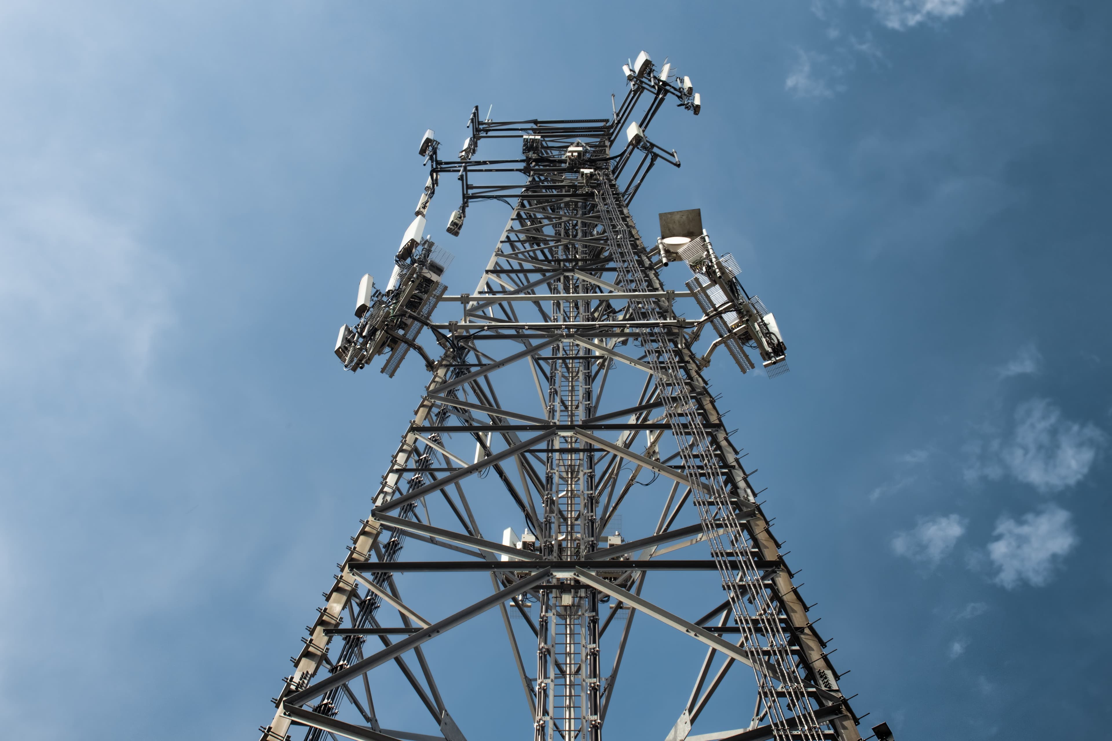 Communications tower carrying multiple antennas against a blue sky